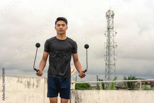 фотографія A young handsome asian man holding a cordless jumping ropes outside a floor deck