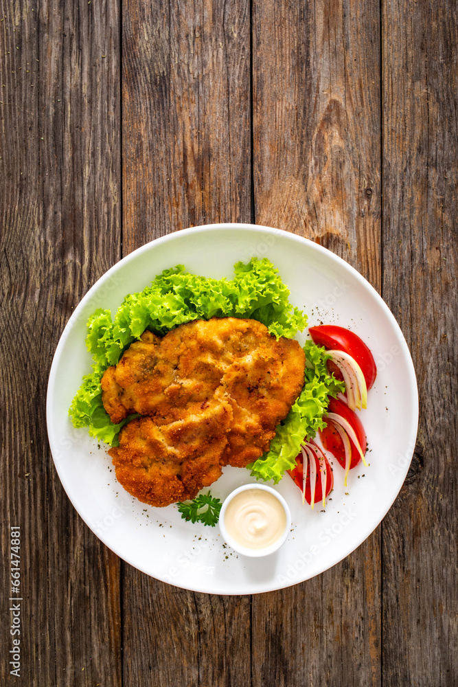 Crispy breaded seared chicken cutlet with lettuce and tomatoes on wooden table
Crispy breaded seared chicken cutlet with lettuce and tomatoes on wooden table
