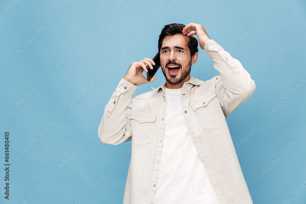 Portrait of a brunette man talking on the phone mobile and internet online, smile with teeth surprise and happiness, on a blue background in a white T-shirt, copy space Portrait of a brunette man talking on the phone mobile and internet online, smile with teeth surprise and happiness, on a blue background in a white T-shirt, copy space