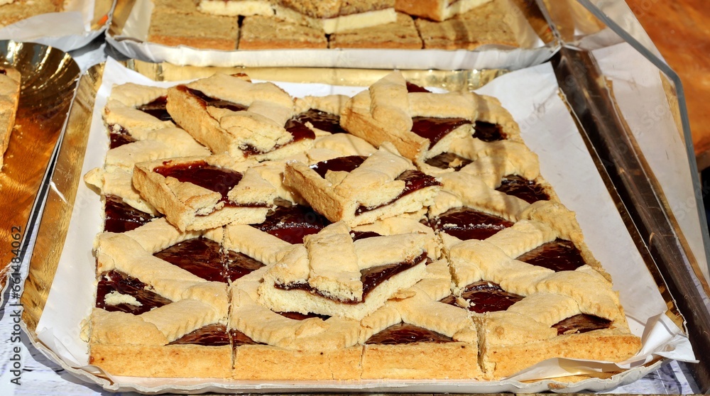 Berry tart cut into squares on the street food pastry shelf.