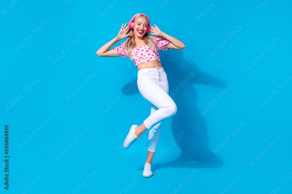 Full body photo of pretty young girl enjoy listen music dressed stylish pink cherry print outfit isolated on blue color background