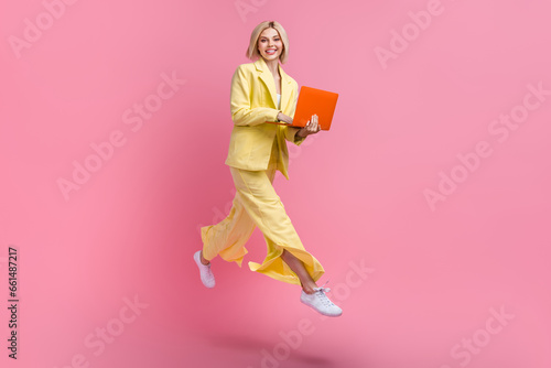 Full size profile photo of gorgeous excited girl jump rush use netbook isolated on pink color background