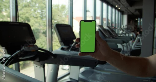 Wallpaper Mural back view of fitness man using green screen smart phone at home. Man preparing for workout using smart phone. man using mobile phone while resting during fitness training Torontodigital.ca