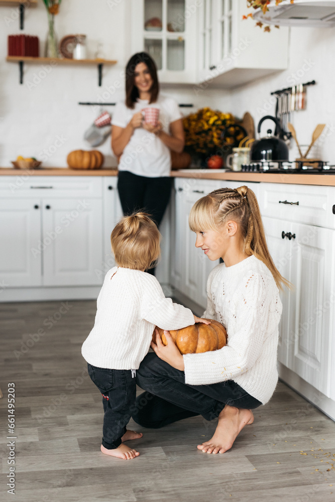family prepares pumpkins for Halloween. Photo on a light background of a happy family surrounded by pumpkins. Parents help children family prepares pumpkins for Halloween. Photo on a light background of a happy family surrounded by pumpkins. Parents help children