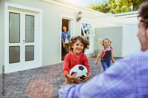 Young children running to the arms of their absent father in the driveway photo