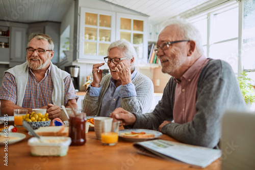 Senior friends having breakfast together in the kitchen