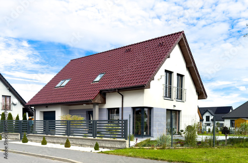 Elegant single family house in Poland seen from the street, fence and roof as main features.