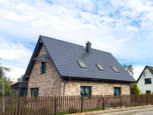 Elegant single family house in Poland seen from the street, fence and roof as main features. Dutch style bricks exterior.