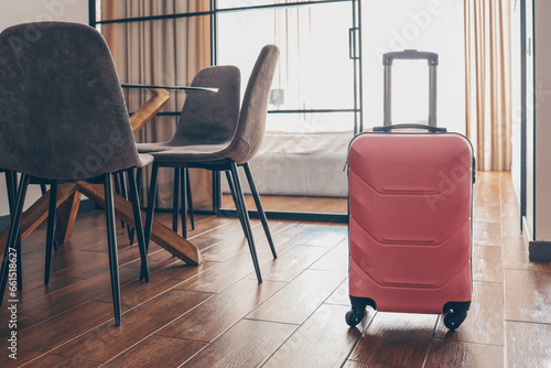 Pink suitcase in light hotel room