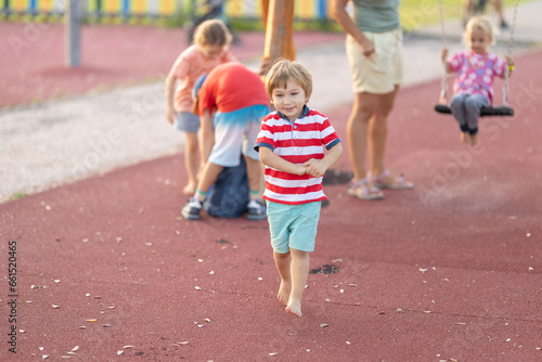 Little cute boy walking on the playground with other kids © KONSTANTIN SHISHKIN