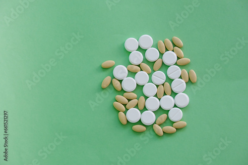 Close up top view heap of pills vitamin supplement on green background. Medical health care pharmacy concept background. Open space area.