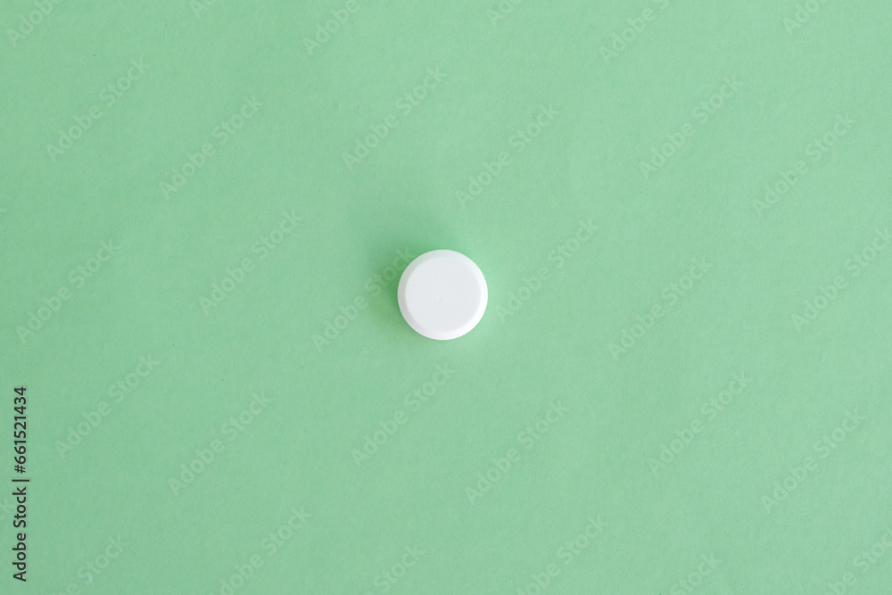 Close up a white pill on green background. Medical health care pharmacy concept background. Selective focus included. Open space area. Close up a white pill on green background. Medical health care pharmacy concept background. Selective focus included. Open space area.