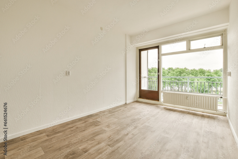 Obraz premium an empty room with white walls and wood flooring, looking out onto the balcony from the living room door