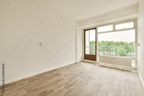 an empty room with white walls and wood flooring, looking out onto the balcony from the living room door