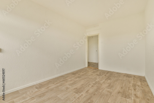 an empty room with white walls and wood flooring on the right side of the room, there is a door that leads to another room