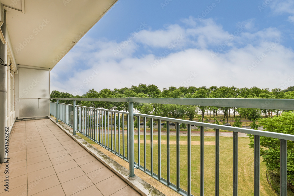 a balcony with blue sky in the background and green trees on the other side of the photo is taken from outside