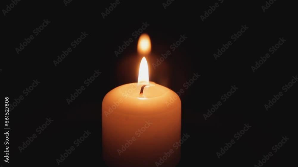 A candle burns on a dark background. A candle glows in the dark, it burns and after a while a gust of wind tries to extinguish the fire A candle burns on a dark background. A candle glows in the dark, it burns and after a while a gust of wind tries to extinguish the fire