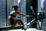 Fitness girl workout on indoor rower at the gym, doing exercises on rowing machine near the window, view of skyscrapers in the background, woman exercising in fitness club
