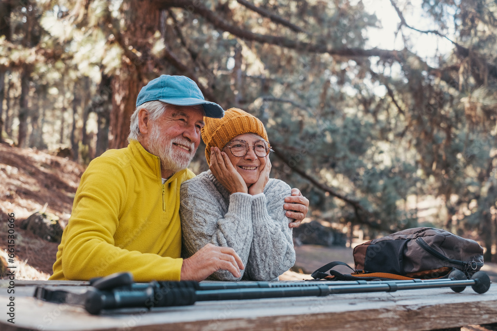 Head shot portrait close up of one middle age woman drinking coffee or tea from a cup sitting at table in the nature in the forest of mountain with old husband hugging wife from the back. Head shot portrait close up of one middle age woman drinking coffee or tea from a cup sitting at table in the nature in the forest of mountain with old husband hugging wife from the back.