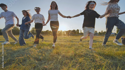 School friends running across the field holding hands at sunset.