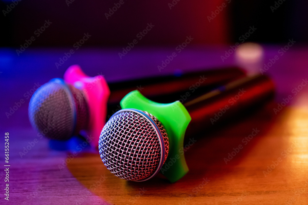 Obraz premium Two microphones with a pink and green attachment are lying on the table. Karaoke, bar concept