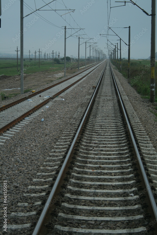 A sleek train track stretches across vast open plains