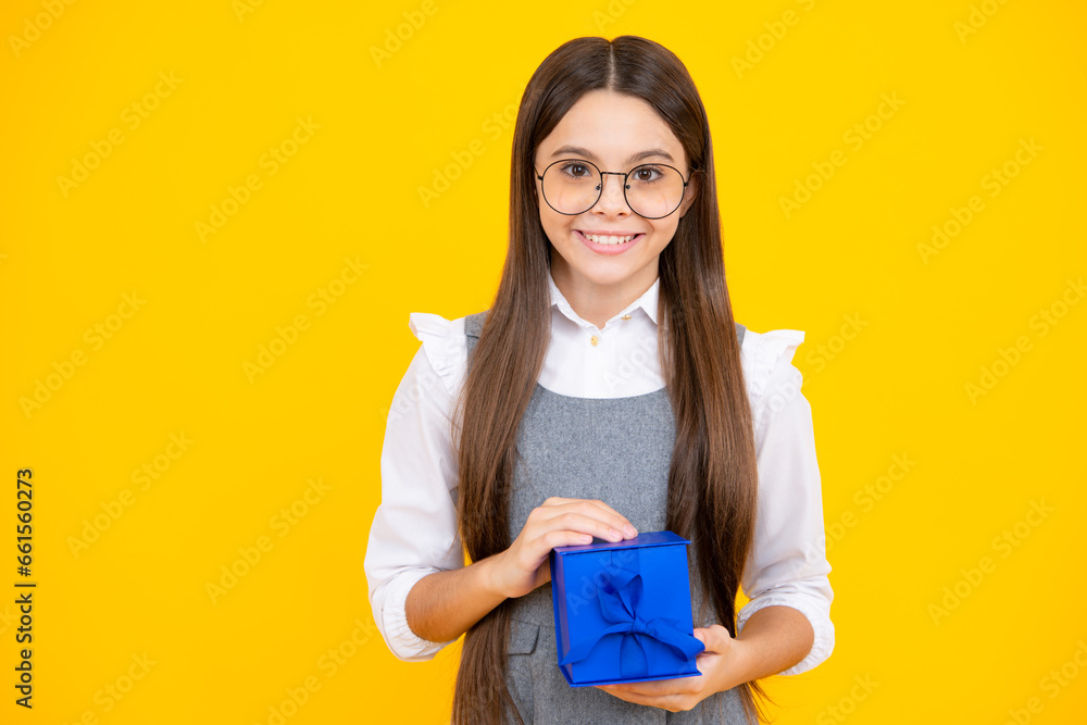 Portrait of a teenager child girl holding present box isolated over yellow studio background. Present, greeting and gifting concept. Birthday holiday concept. Portrait of a teenager child girl holding present box isolated over yellow studio background. Present, greeting and gifting concept. Birthday holiday concept.