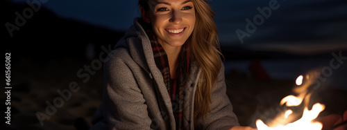 Woman relaxing around a campfire on the beach at night with her friends