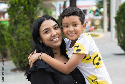 Portrait of a latina mother hugging her son smiling and looking at the camera.