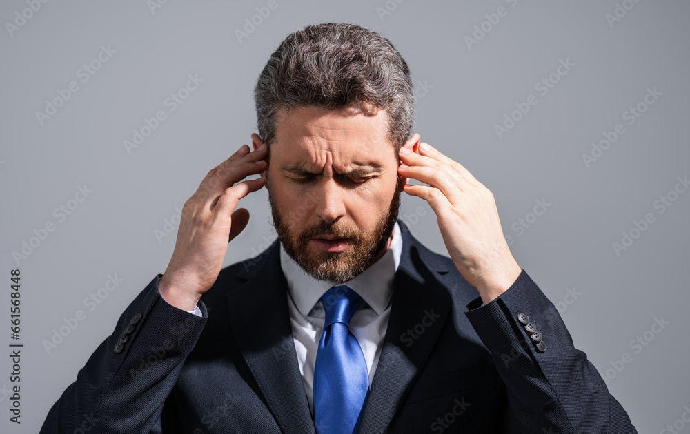 Stressed business man in suit having headache. Tired businessman is working overtime and has headache. Overworked man suffers from headache. Migraine from overwork, deadline, difficult at work. Stressed business man in suit having headache. Tired businessman is working overtime and has headache. Overworked man suffers from headache. Migraine from overwork, deadline, difficult at work.