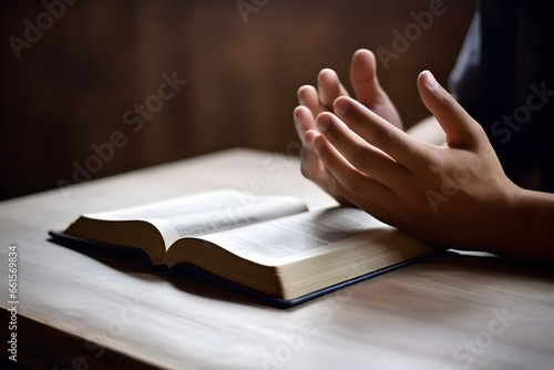Hands together in praying to God along with the holy bible book photo