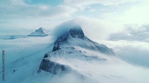 Photo of a majestic snow-covered mountain surrounded by clouds