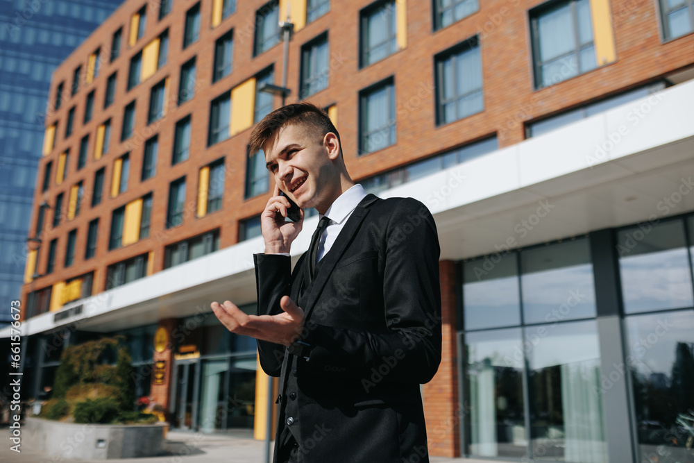 A young and expressive Caucasian businessman in a sleek suit, engaged in a phone conversation outdoors, captures the essence of urban connectivity and communication. A young and expressive Caucasian businessman in a sleek suit, engaged in a phone conversation outdoors, captures the essence of urban connectivity and communication.