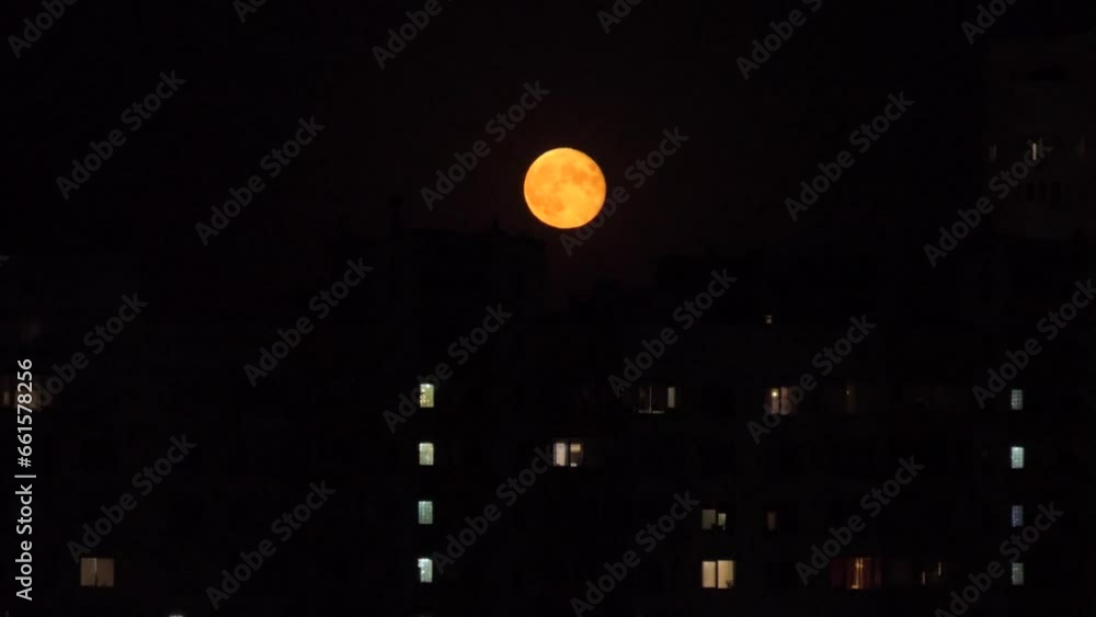 The full moon rose over multi-story buildings in the city The full moon rose over multi-story buildings in the city