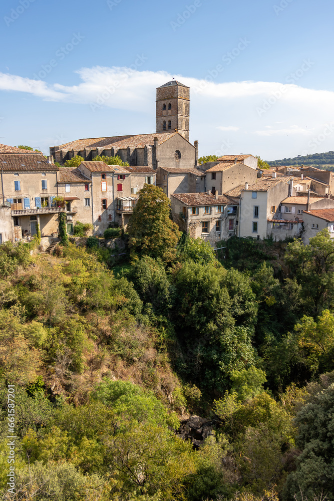 A view of the village of Montolieu Aude Languedoc - Roussillon France. Trees valley ancient houses and church bell tower.
