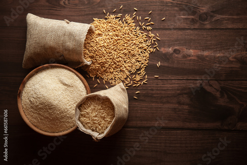 Top view of organic Rice (Oryza sativa) flour in a wooden bowl and raw stages of rice in a jute bag.