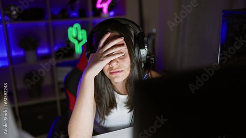 Stressed hispanic streamer, beautiful young woman overworked streaming gaming under duress at home photo