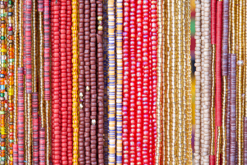 close up on strings of beads in reds, yellows, pinks. Popular hair decorations in some cultures.