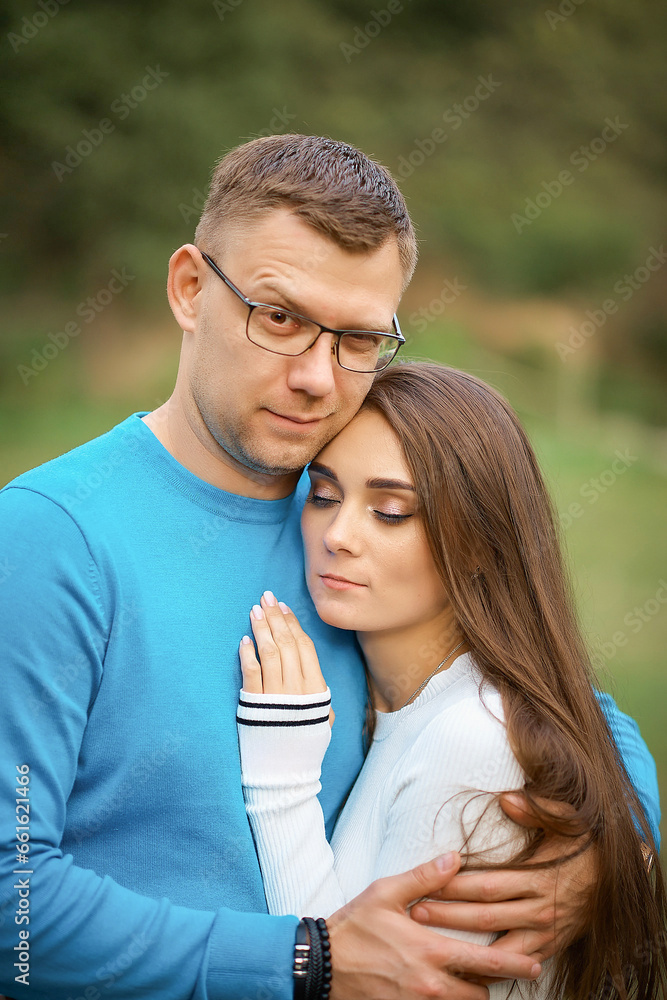 Beautiful happy couple hugging while walking. The guy looks at the camera and smiles Beautiful happy couple hugging while walking. The guy looks at the camera and smiles