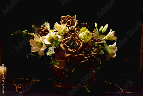 Close-up of a bouquet of roses, Lily, and other flowers in a vase on a black background.