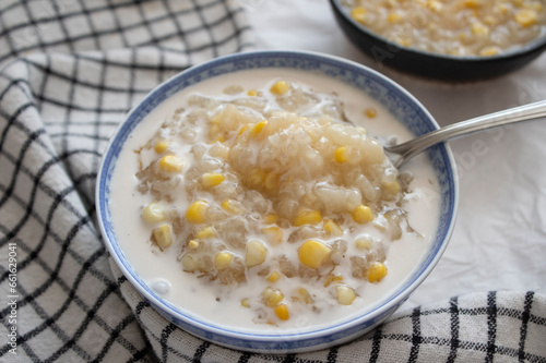 Top view of a bowl of fresh corn and sticky rice pudding dessert with coconut milk.