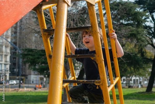 A little boy climbing the slide stairs to slide on the playground