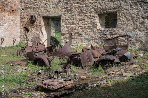 Scrap metal remains of a car and a tractor from a farmer's house that was burned during the war
