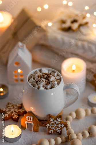 Winter delicious gourmet christmashot drink. Chocolate or cocoa with marshmallow and spices on white background. Gingerbread cookies, candles. Cozy home atmosphere, festive vibes