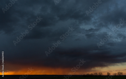 Landscape at sunset. A thunderstorm is approaching the village. Tragic gloomy sky. Panorama. © Piotr