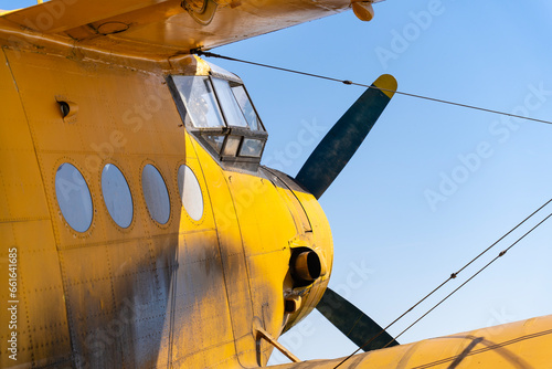 Cockpit of an old yellow-painted airplane with the blue sky in the background