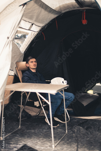 A young man is sitting at a table in a tent in a store.