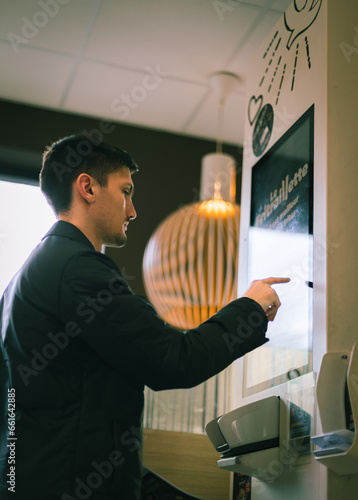Foto A young man makes an order for fast food on a scoreboard screen in a diner