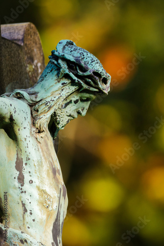 close up of crucifix in profile in front of autumn forest in blurred background