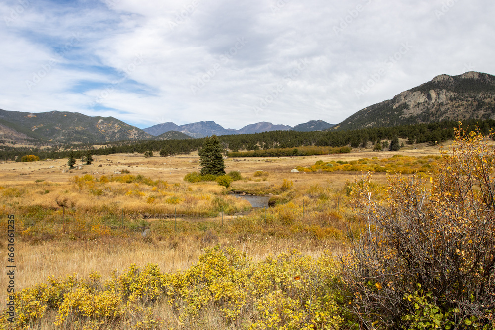 Rocky Mountain National Park, Colorado, USA on September 30, 2023.  Landscape photograph of a golden field with a stream and the Rocky Mountains in the distance.  